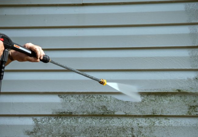 An,Unidentified,Man,Uses,A,Power,Washer,To,Clean,Mold